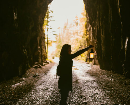 Woman standing in a cave holding a lantern